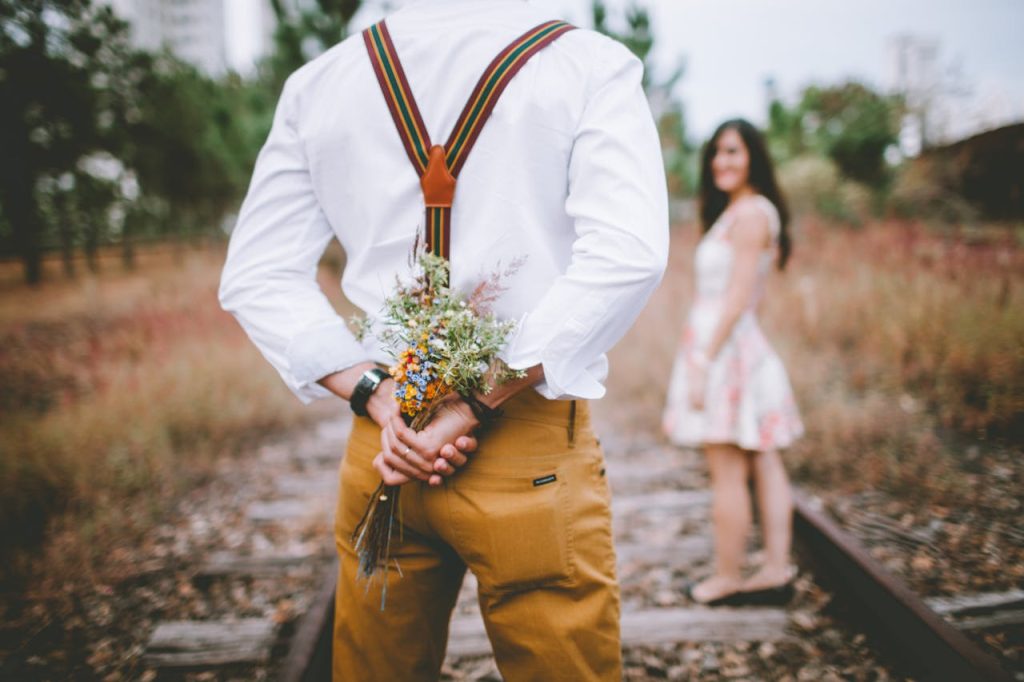 A romantic surprise proposal with a bouquet on an abandoned railway track.